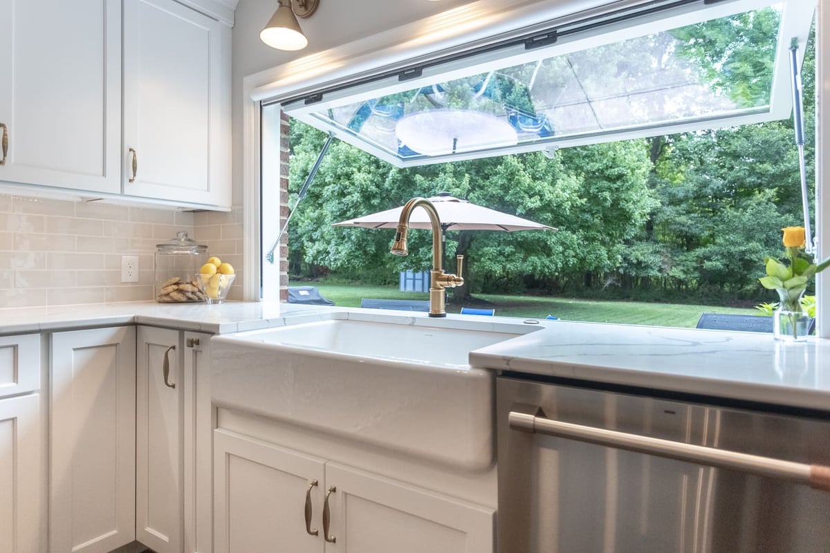 Farmhouse-style sink with brass hardware and pass-through awning window in Cincinnati kitchen remodel by Legacy Builders