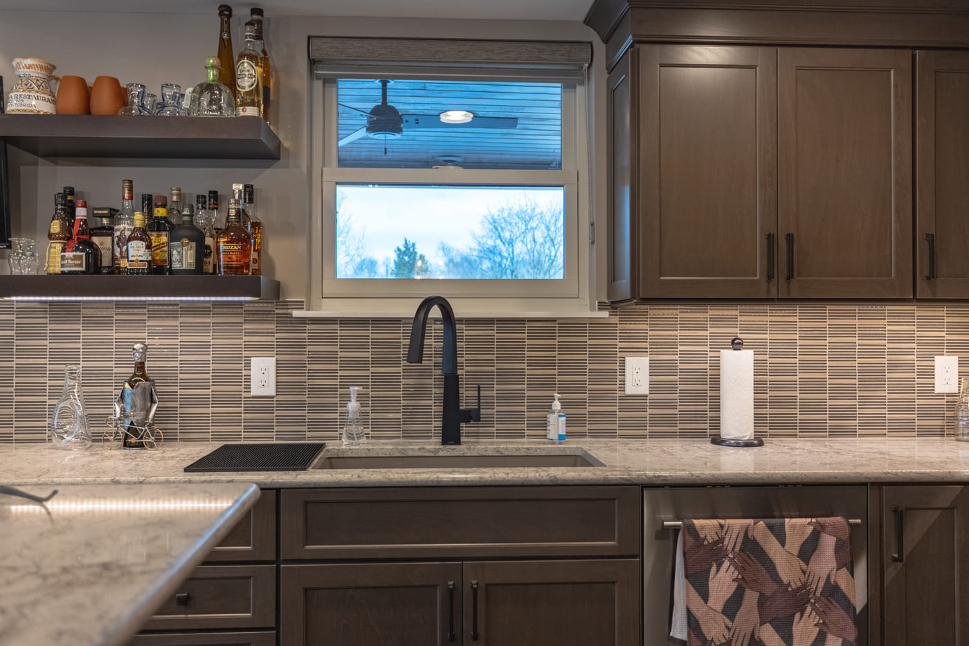 Custom basement bar area with shaker cabinets and mosaic backsplash behind sink in Ross County, OH