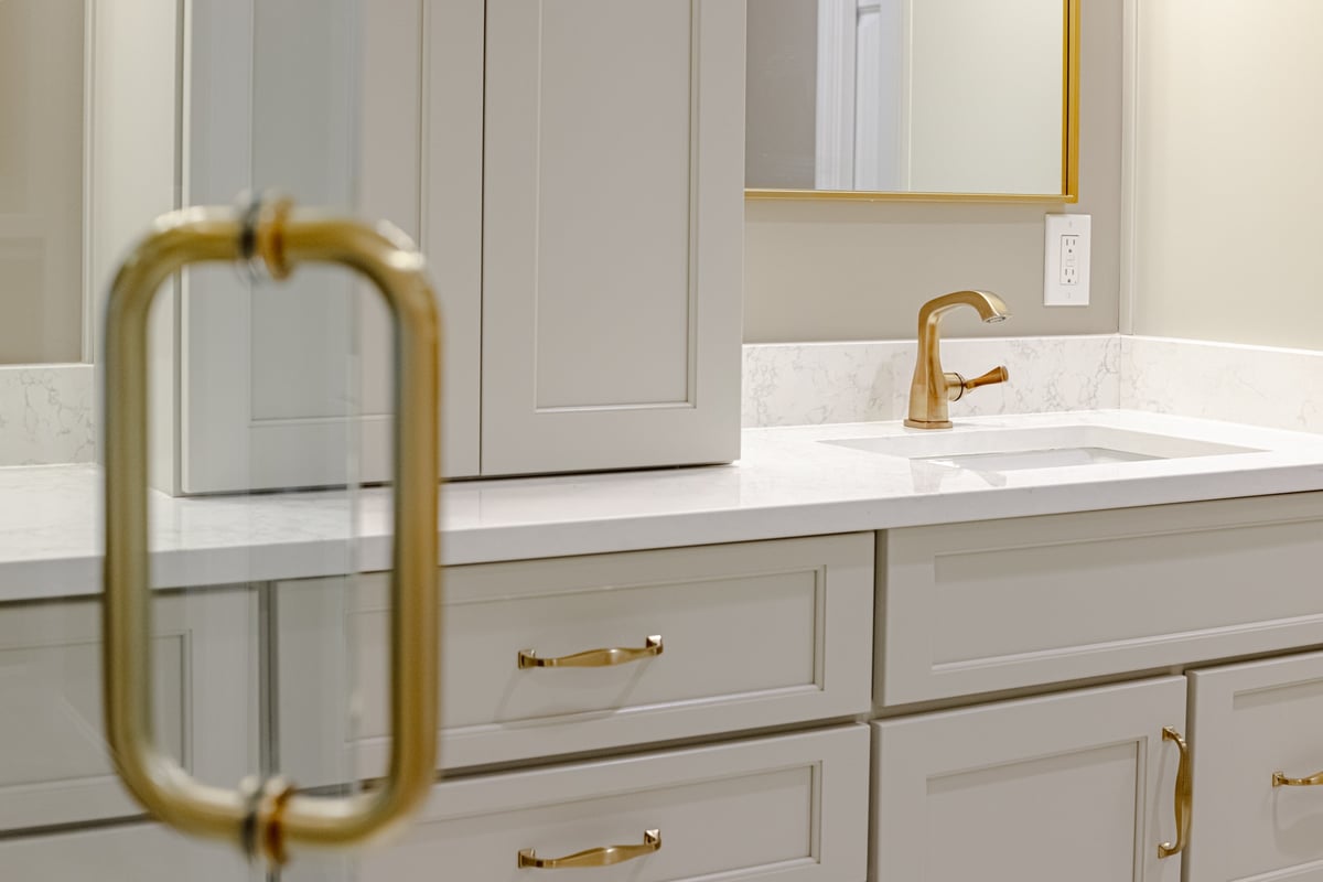 Brass bathroom fixtures on sink and walk-in shower door in Cincinnati remodel by Legacy Builders