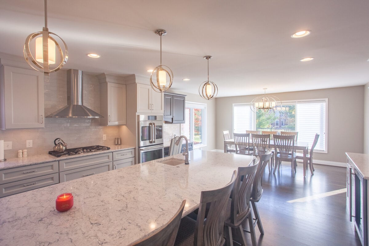 White Oak addition interior with three pendant lights above island and view of dining room by Legacy Builders