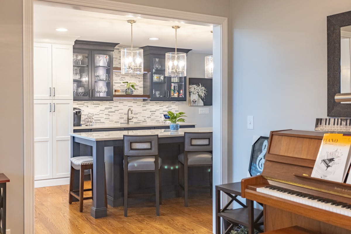 View of kitchen island and glass-front cabinets above sink at beverage station by Legacy Builders