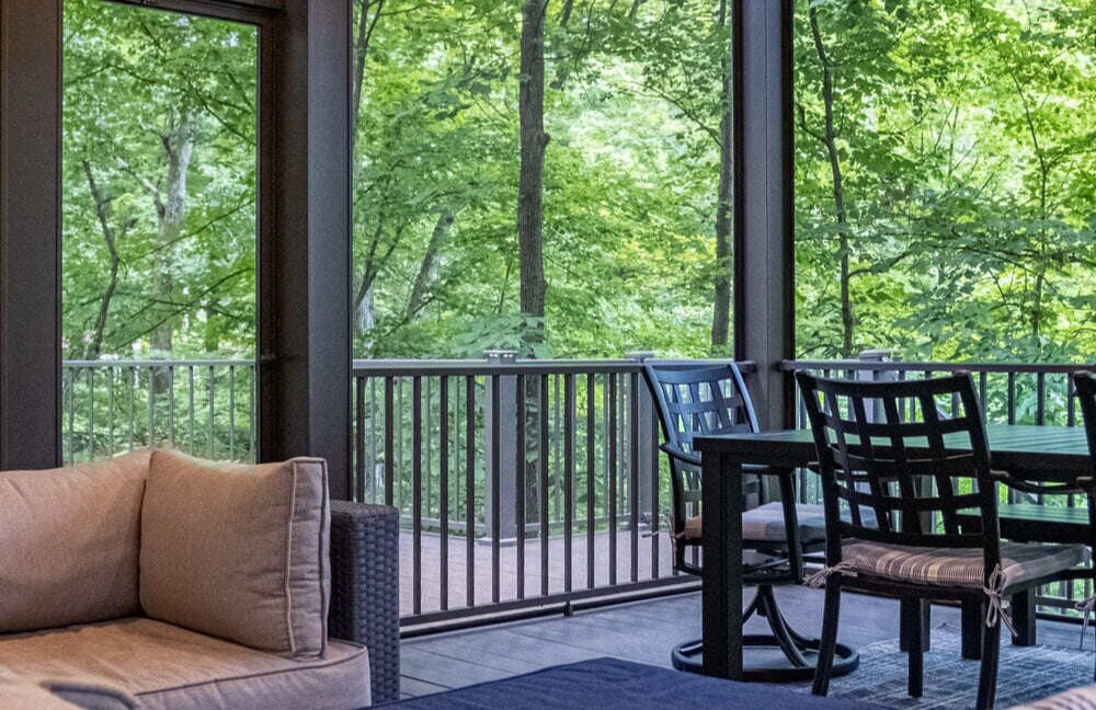 Black outdoor dining chairs with a ceiling fan in an outdoor living addition in Symmes Township, Ohio, by Legacy Builders