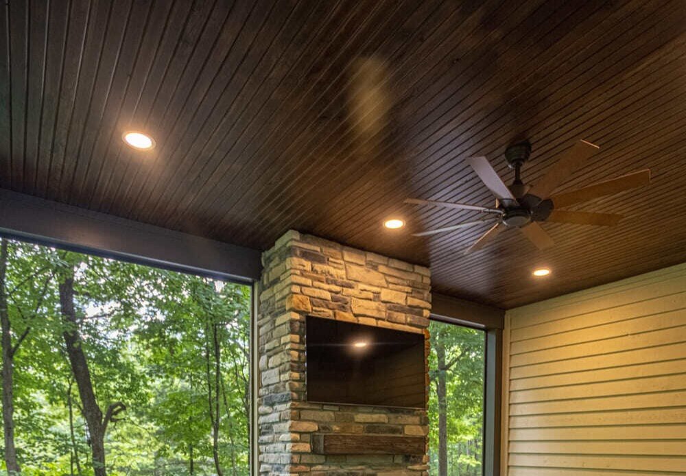 Screened-in porch with a stone fireplace in an outdoor living addition in Symmes Township, Ohio, by Legacy Builders