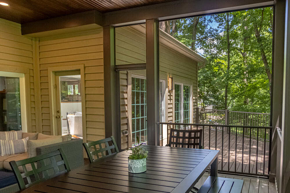 Screened-in porch with black outdoor dining chairs and a table in an outdoor living addition by Legacy Builders